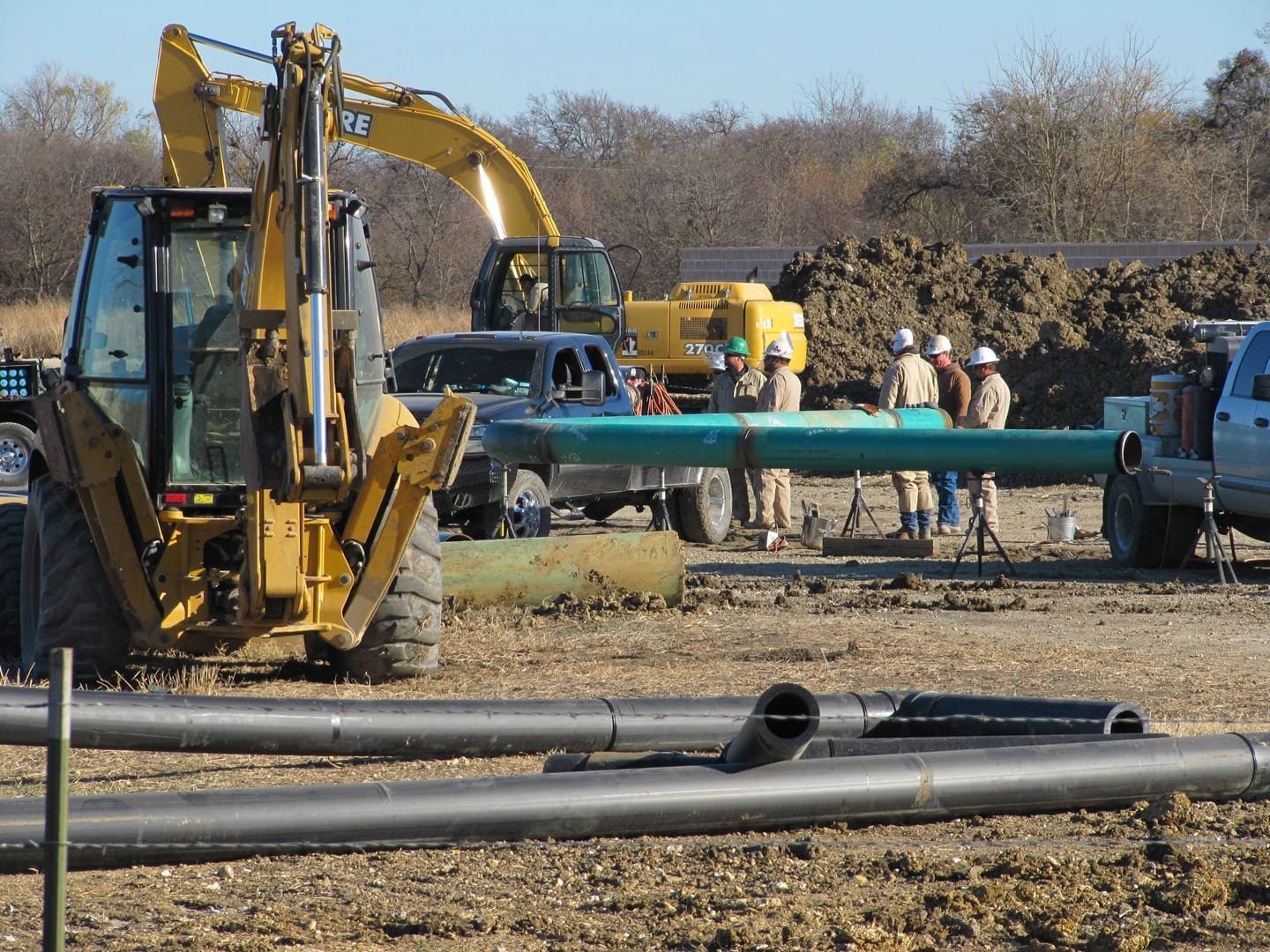 A group of people standing around a pipeline.